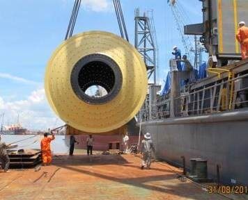 Heavy cylindrical equipment being lifted at a port berth
