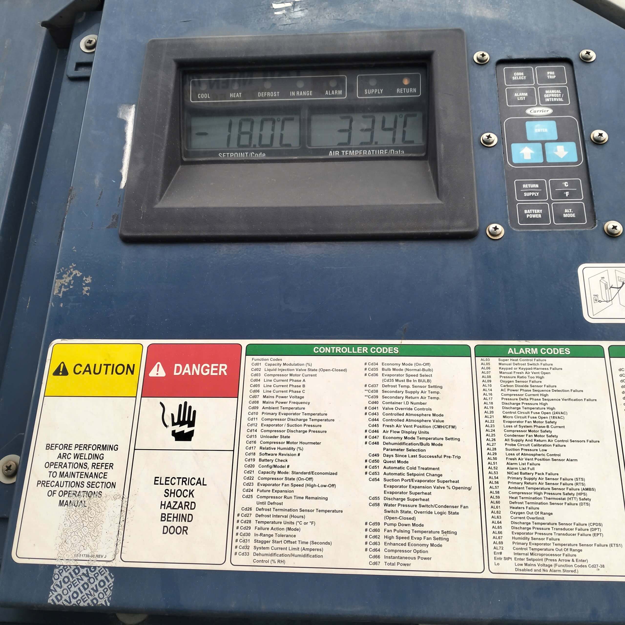Reefer container controller display with the printed chart of controller codes and alarm codes